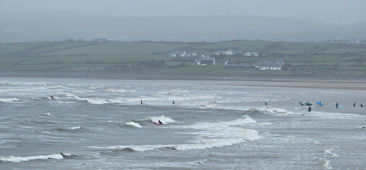 a few beginner surfers in the water at the north end of the beach